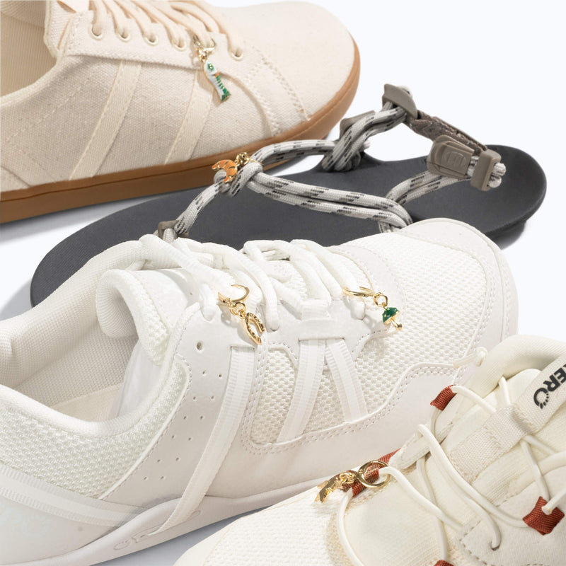 Xero Shoes 5-Piece 'Good Vibes' Charms attached to Off-white and White Sneakers and a Gray Sandal
