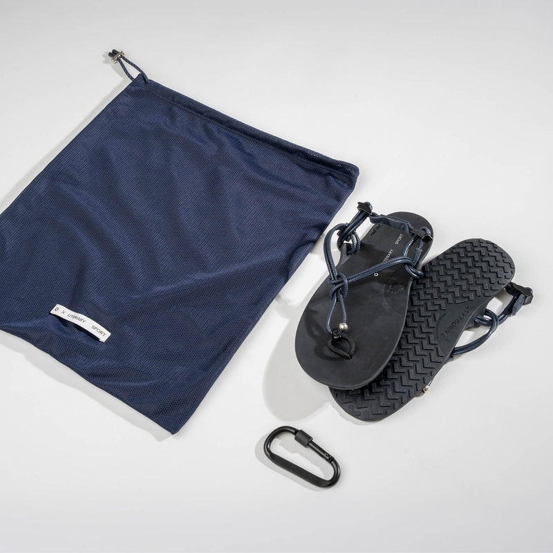 Xero Shoes x Literary Sport Genesis Navy Strap Black Sandal with a Top View Showing Both Sandals, a Matching Mesh Storage Bag, and a Black Carabiner