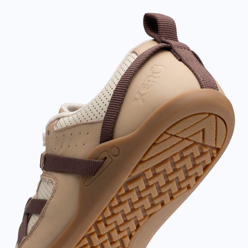 Xero Shoes Prio Leather Shoe in Cream and Brown, Positioned at an Upward Angle with its Textured Rubber Sole Visible and with Toe Facing Bottom Left