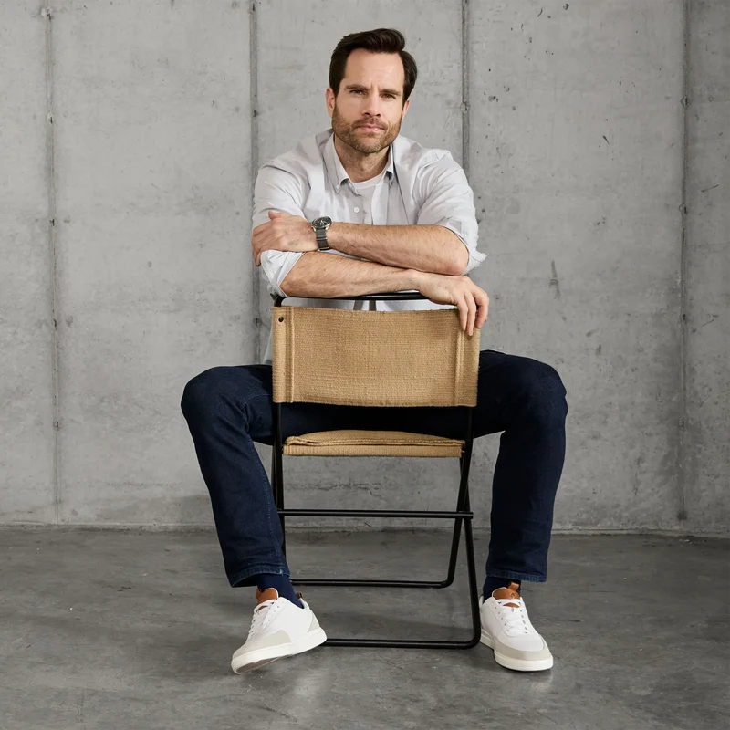 Model wearing The Court in Ivory leather & suede with jeans sitting in chair